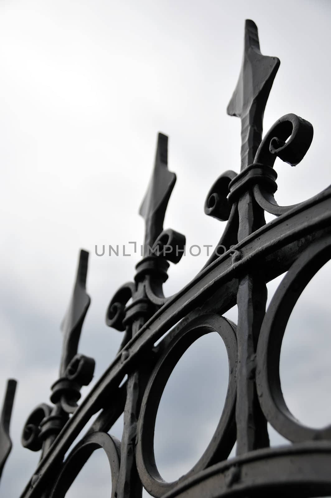 Sharp decorative iron fence against cloudy sky