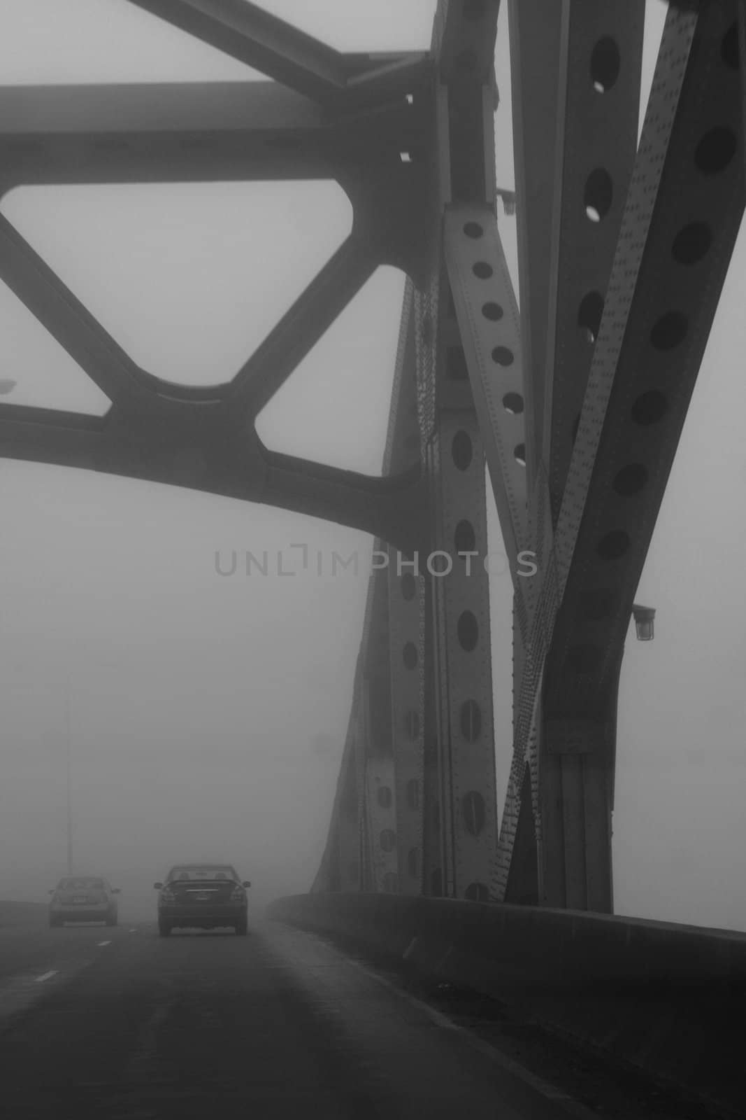 Cars driving over bridge in dense early morning fog