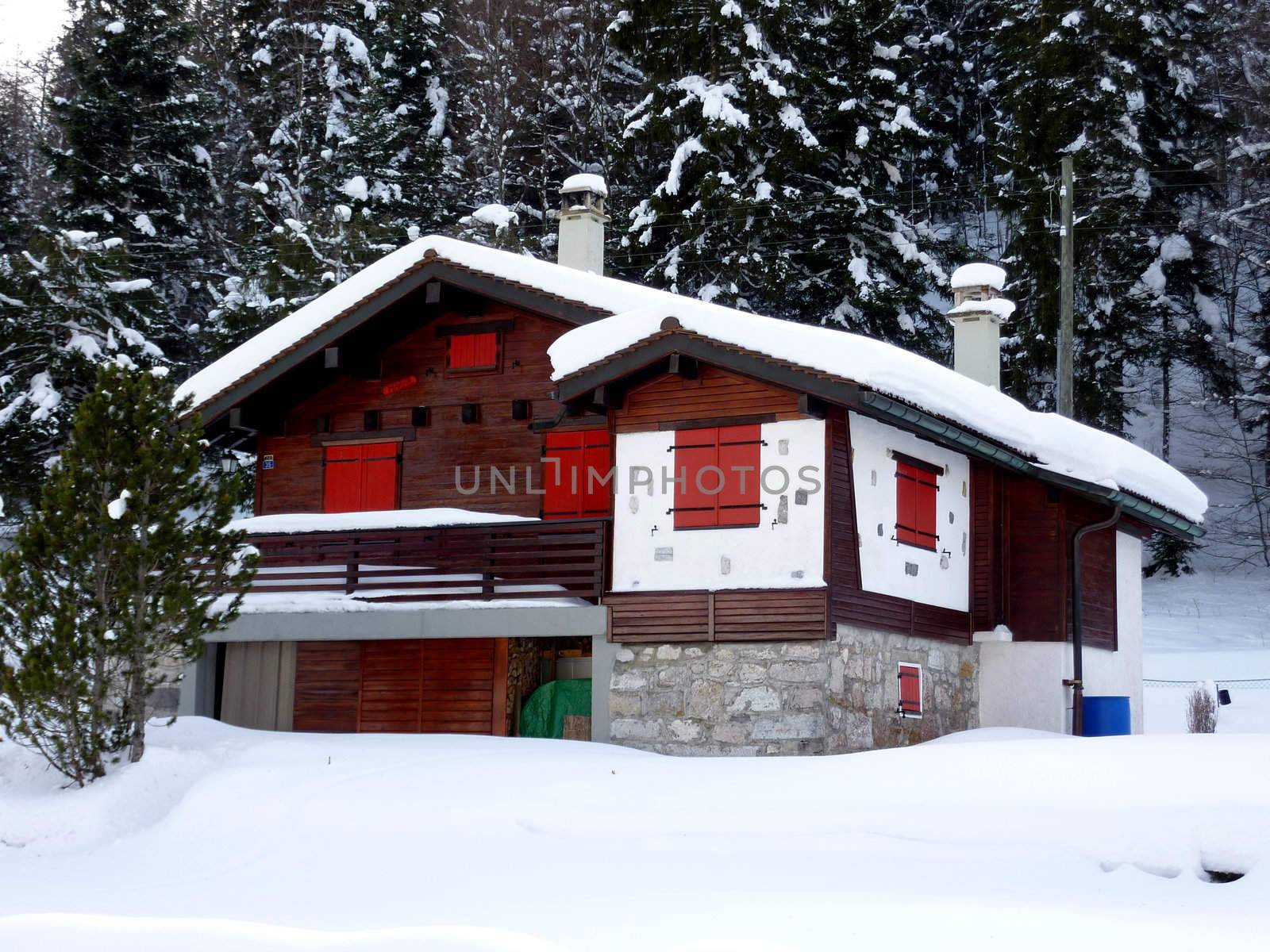 Red shutters on beautiful chalet in Jura mountain, Switzerland, by winter