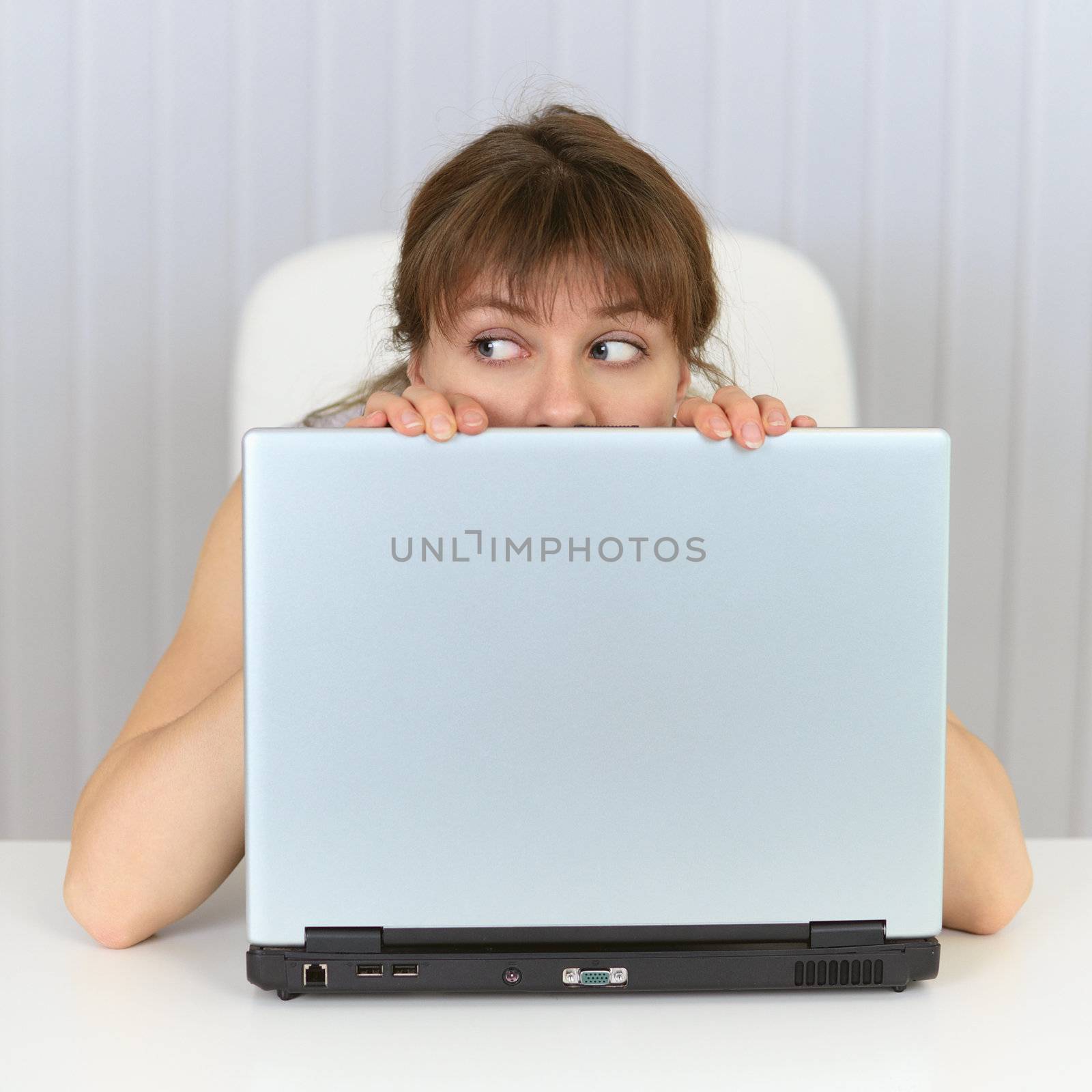 Young woman hiding behind a laptop by pzaxe