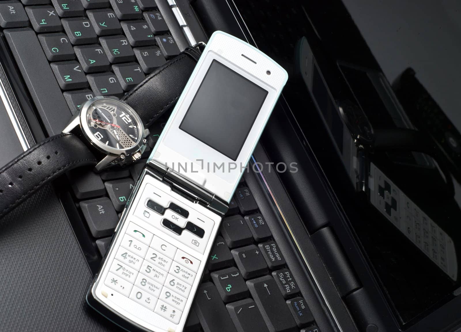 Cellular phone and watch on a laptop
