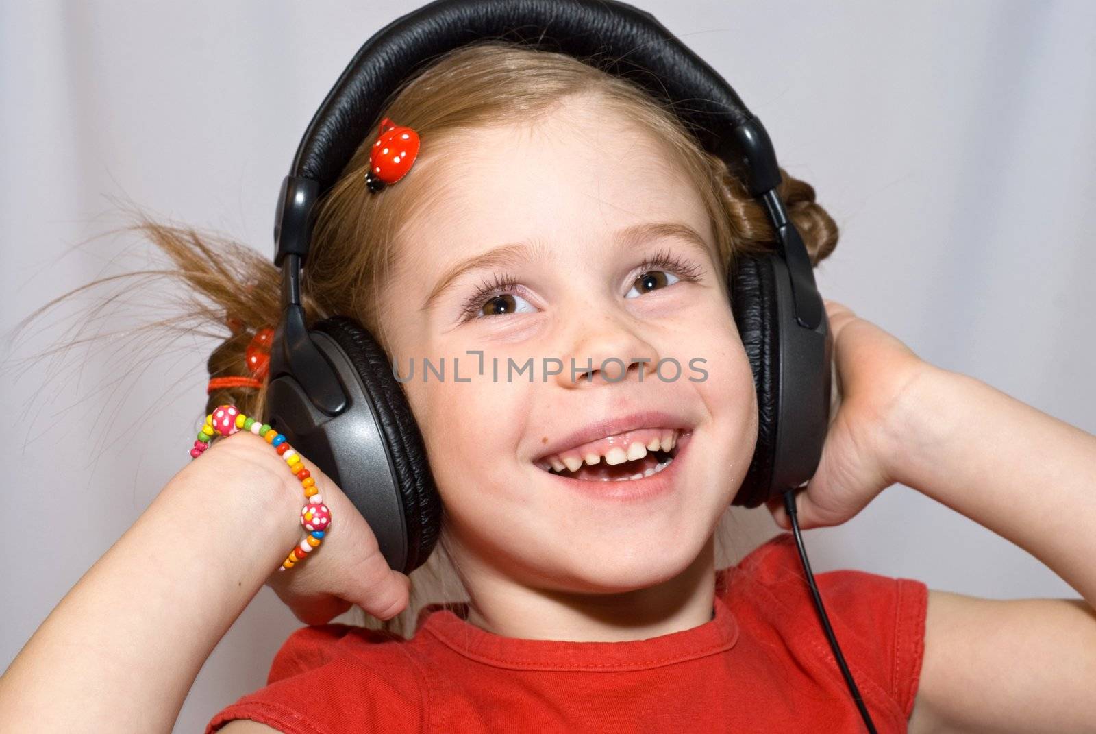 smiling little girl listening to music with headphones