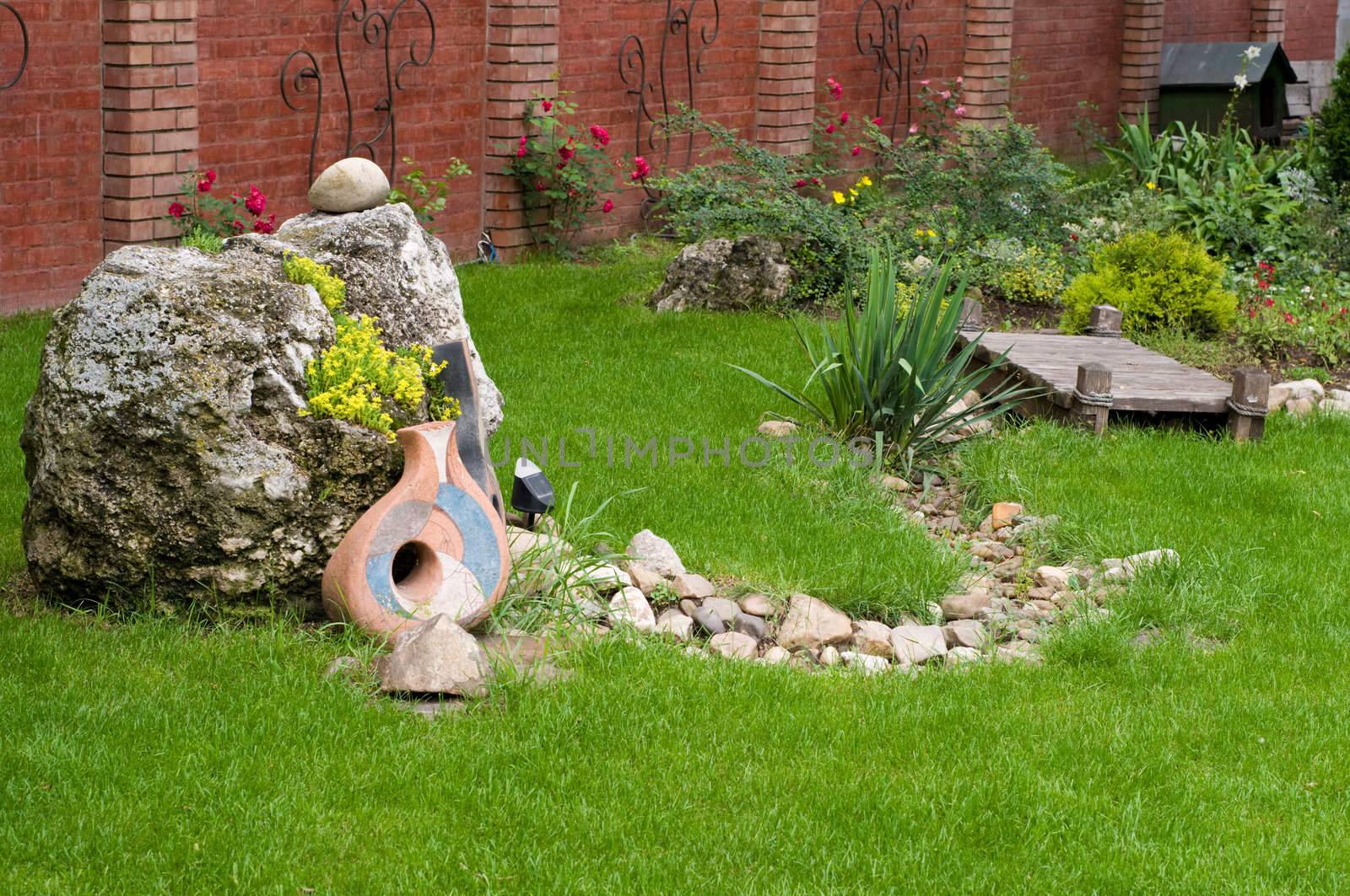 nice backyard decoration, stone with yellow flowers, ceramics on the grass etc