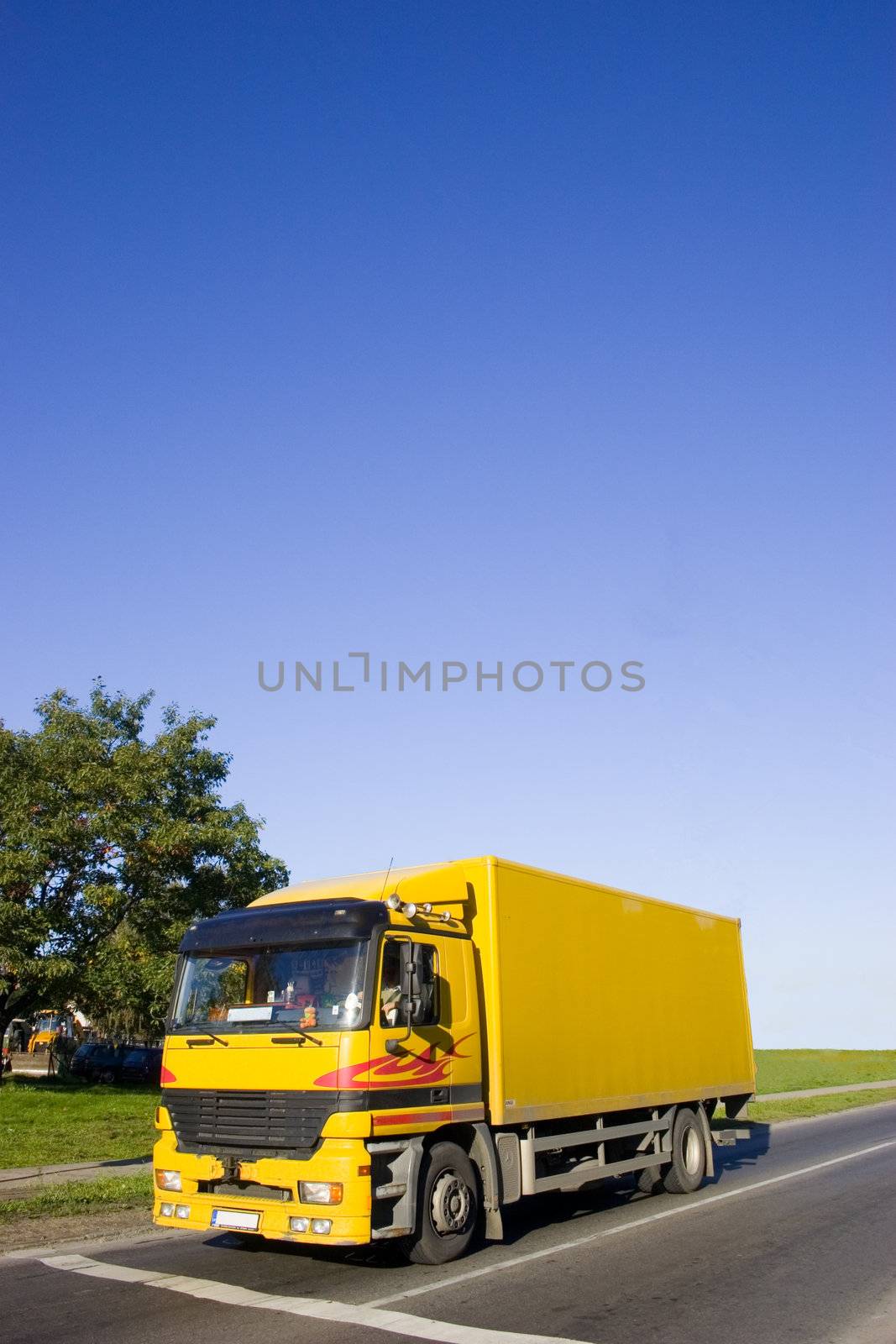 Yellow truck on asphalt road. Large blue sky with place for copy text.
