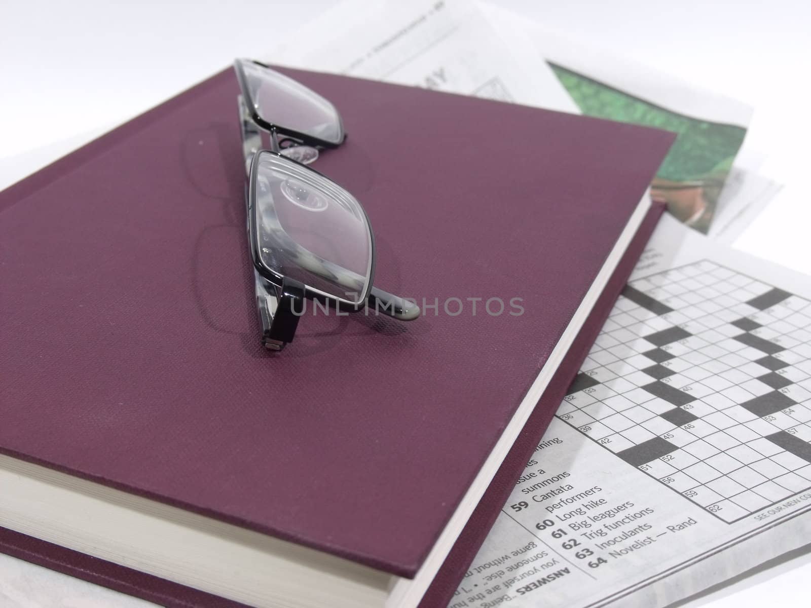 Glasses lying on top of book and newspaper by WarburtonPhotos