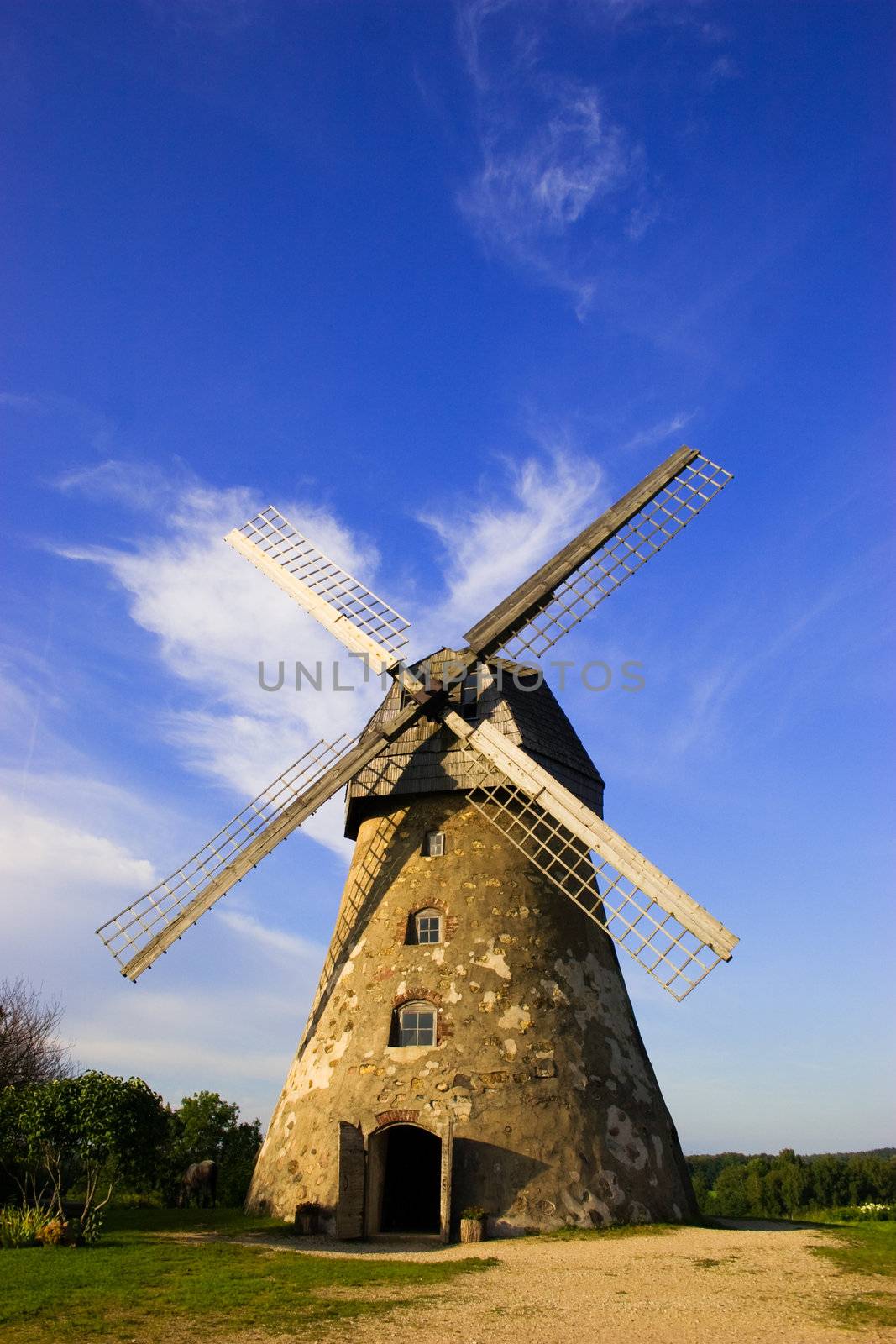 Traditional Old dutch windmill in Latvia against blue sky with white clouds