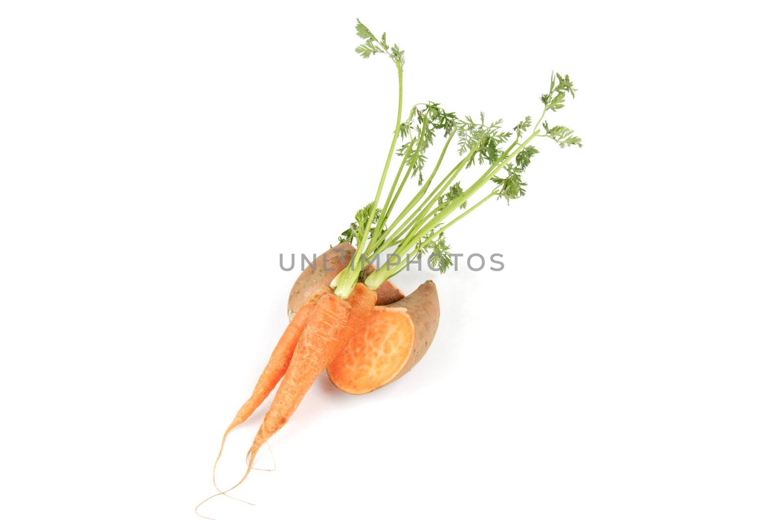 Sweet Potato cut in half with a bunch of raw carrots on a reflective white background