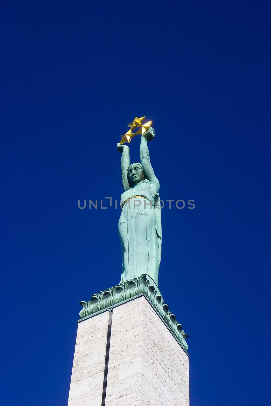 Top part of Monument of Freedom in Riga - copper statue of a woman holding three gold stars which symbolise three regions of Latvia. Main idea of this monument is "To Fatherland and Freedom"