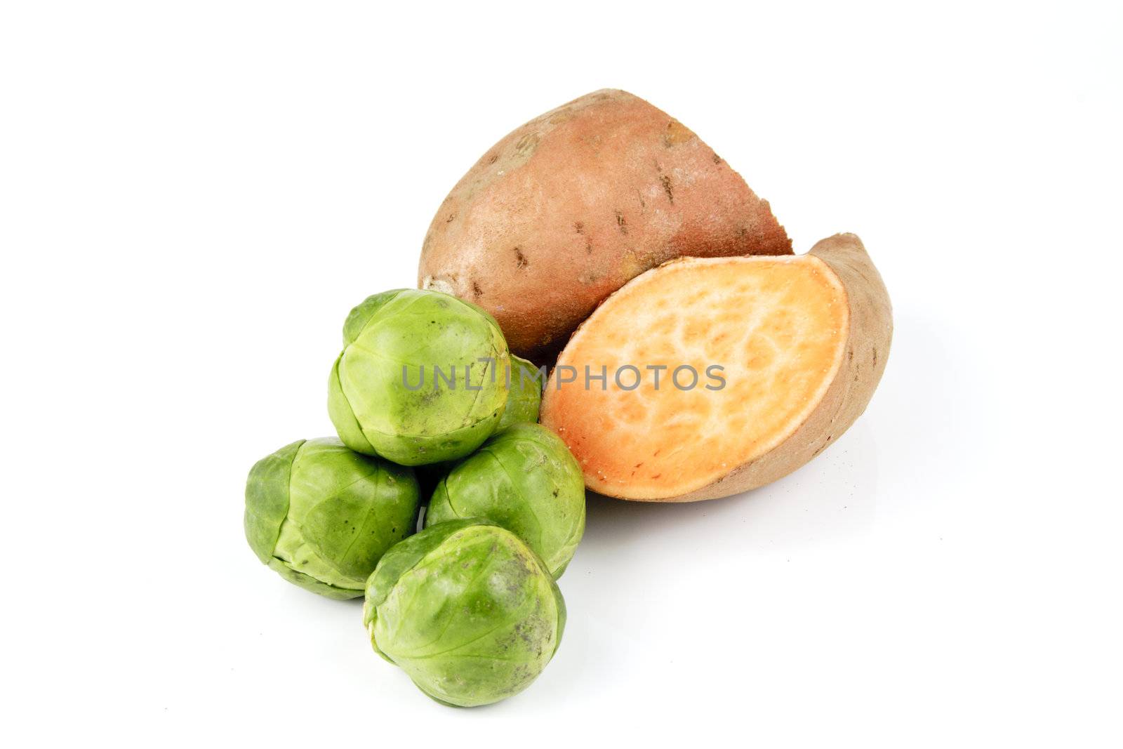 Sweet Potato cut in half with pile of green sprouts on a reflective white background