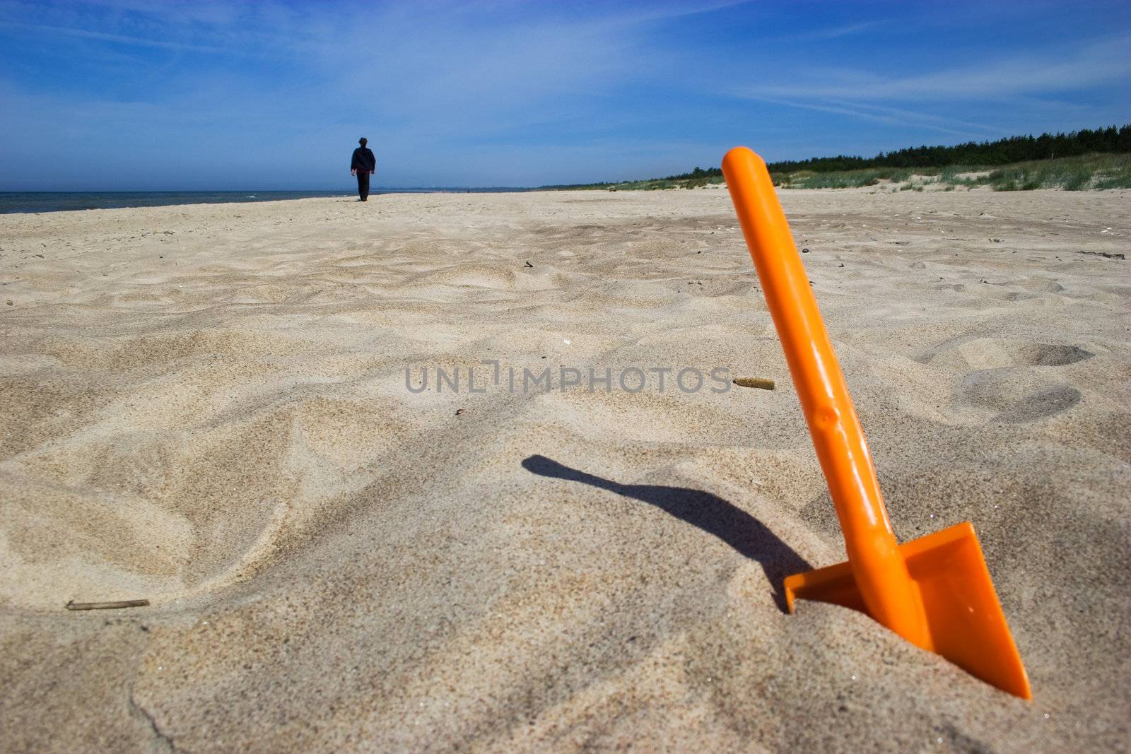 Orange plastic spade in the sandy seashore