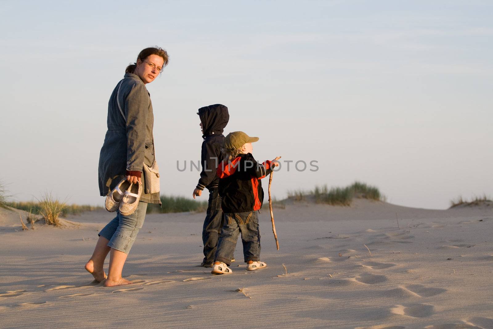 Mother and her sons in sand dunes. Late evening sunset light.