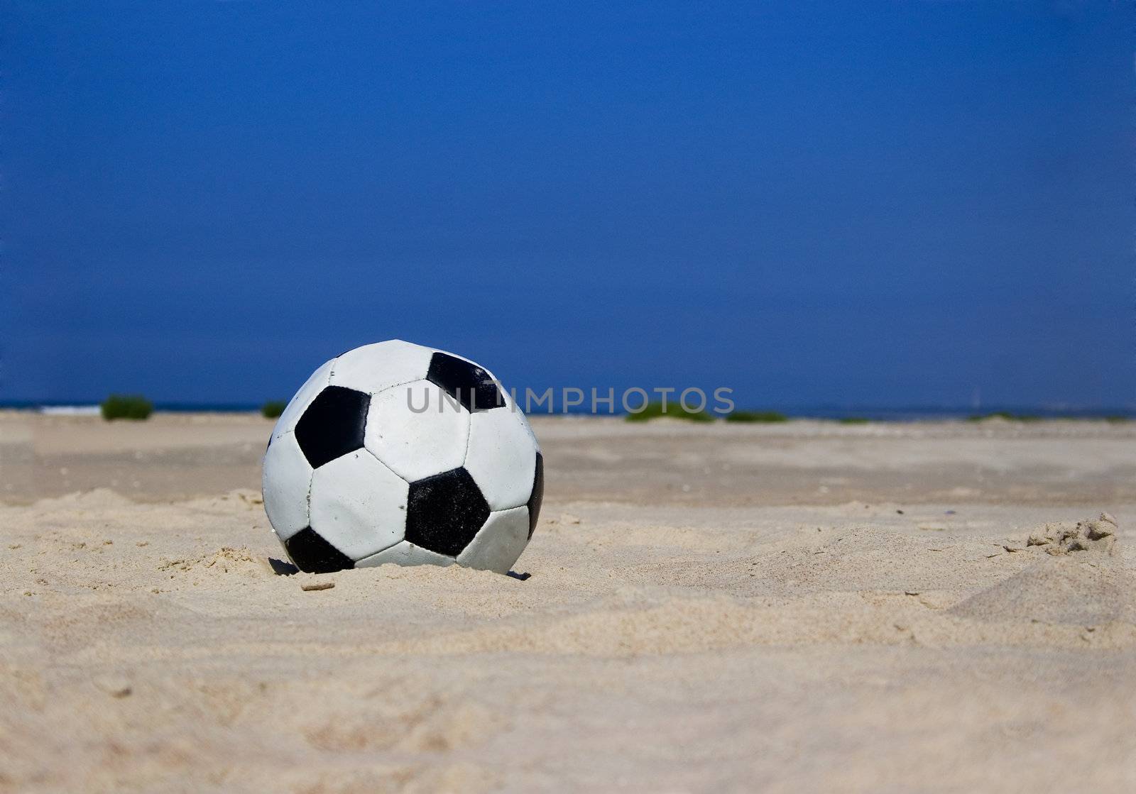 Soccer ball on sandy beach by ints