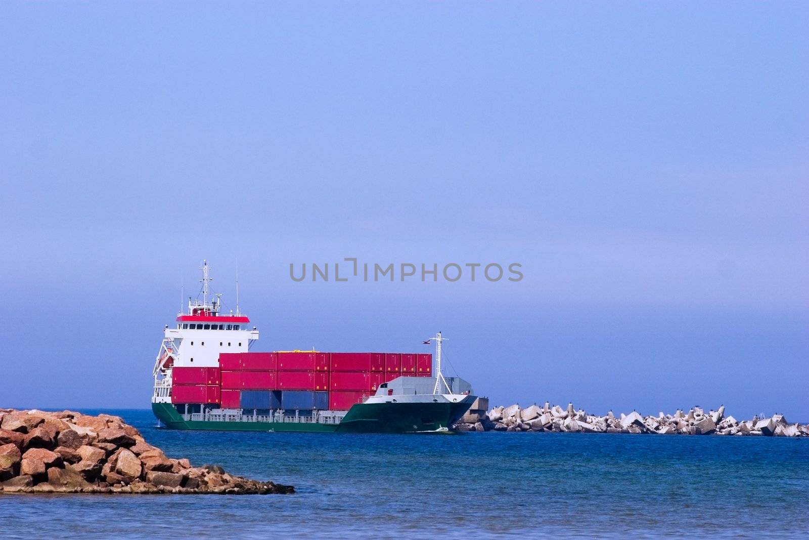 Cargo ship with red containers entering port