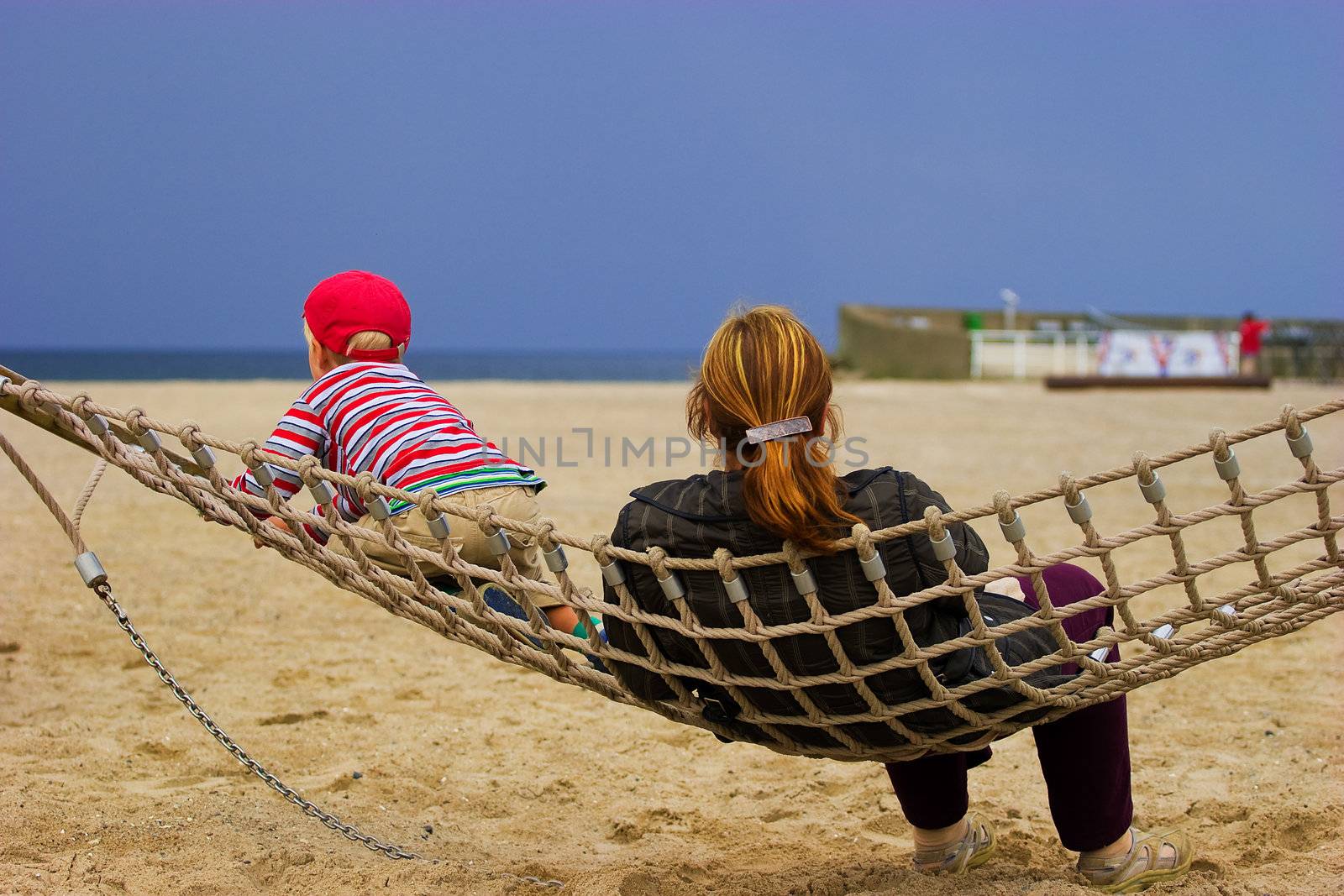 Mother and child in hammock resting at sandy beach