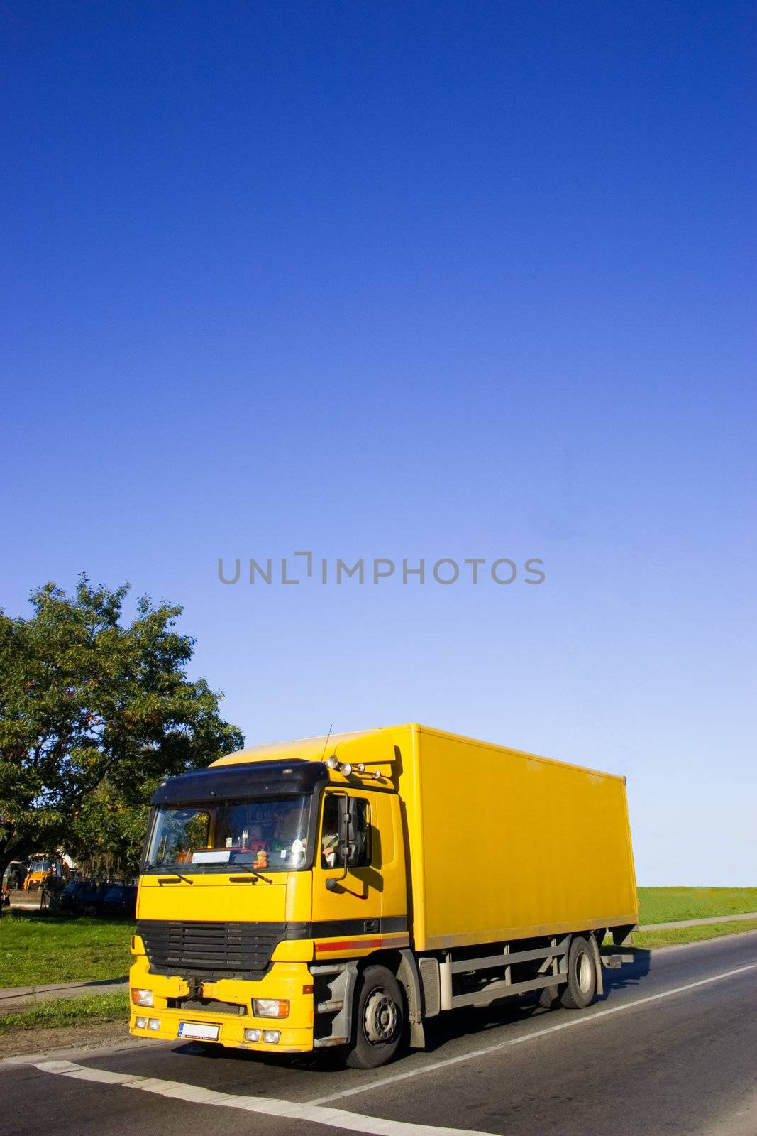 Yellow truck on asphalt road. Large blue sky with place for copy text.