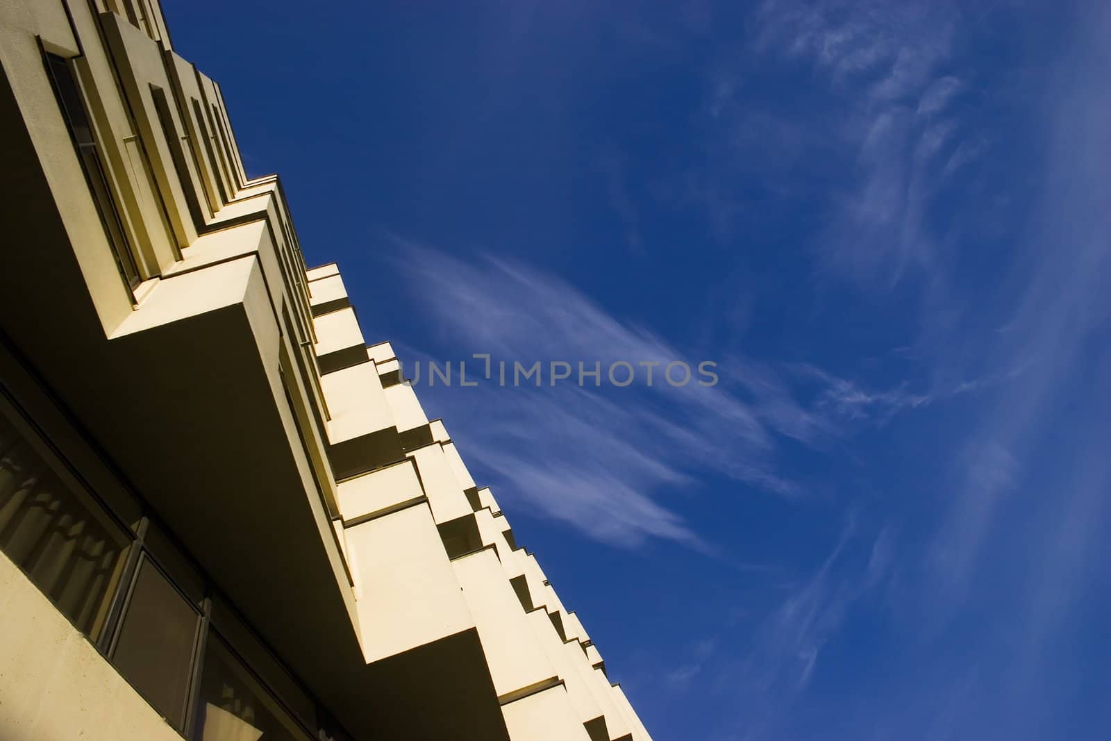 Detail of Beige modern apartment house under unusual viewing angle with blue sky