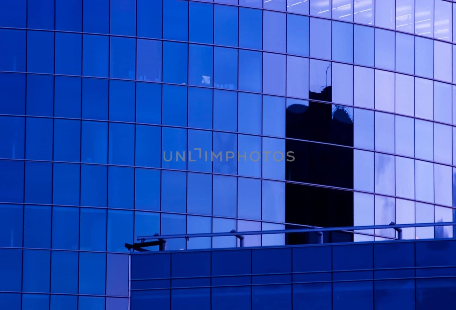Blue corporate office building facade and reflection of other skyscraper in late evening