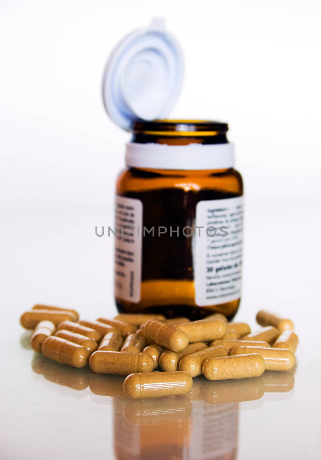 Bunch of pills in foreground und bluried open bottle in backgraound