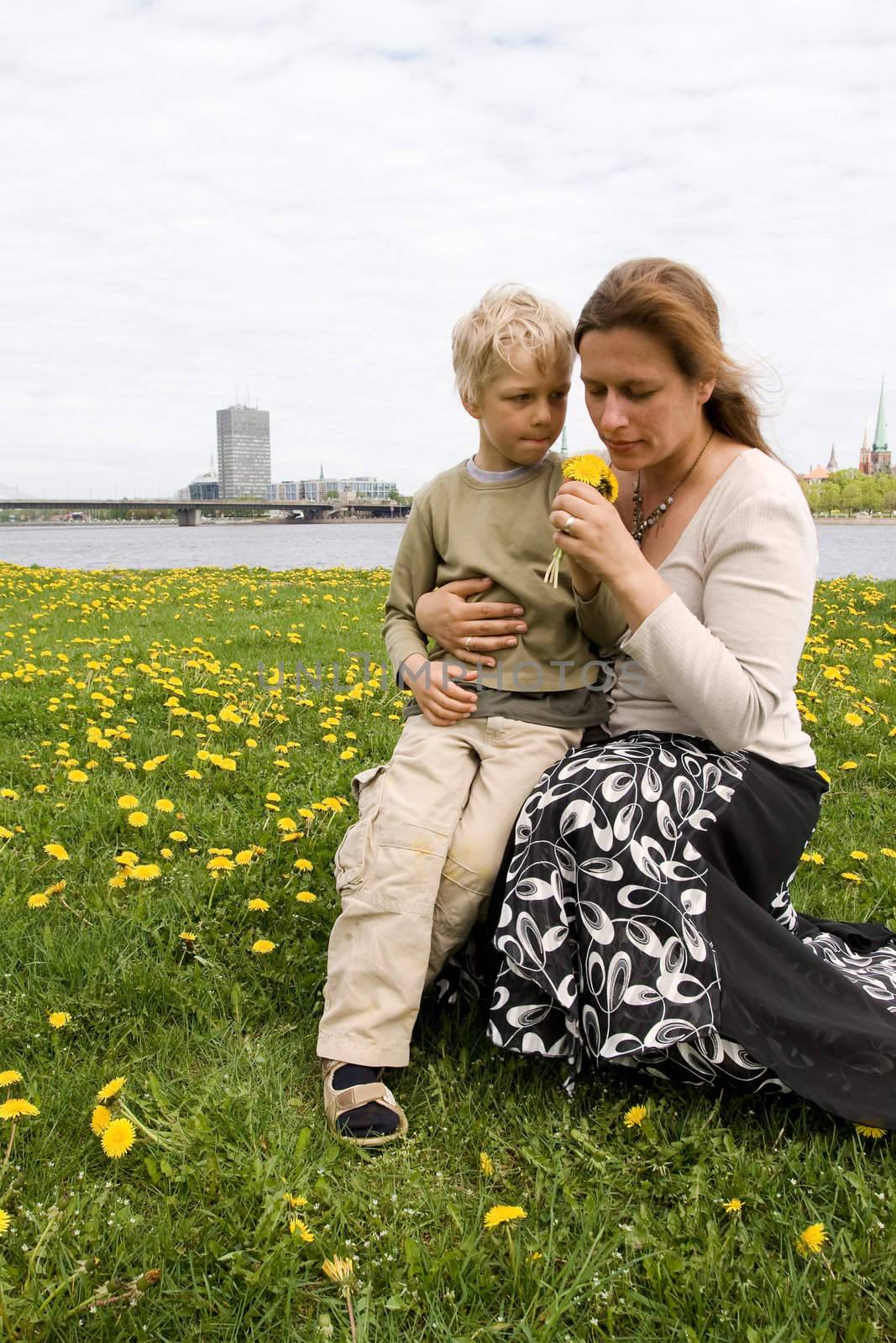 Mother and son in Dandelion meadow. Riga city in background