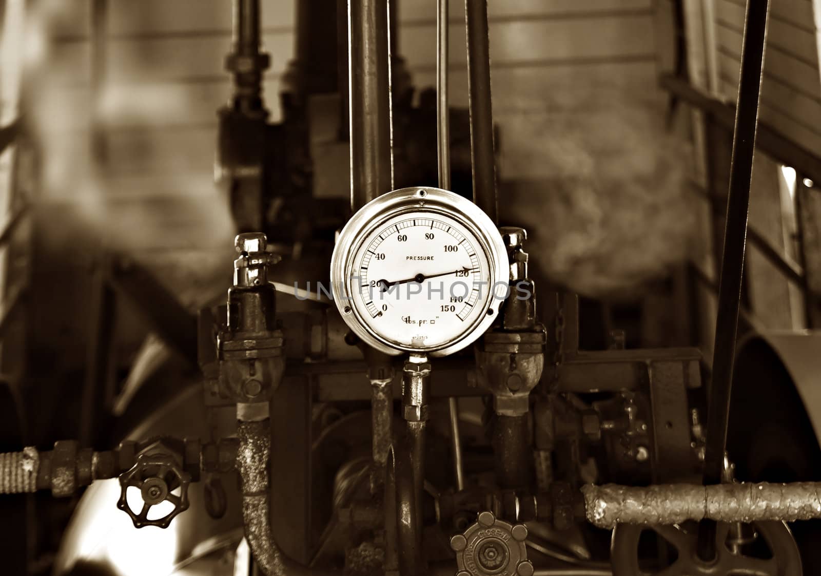sepia image of machinery under pressure gauge lets out steam