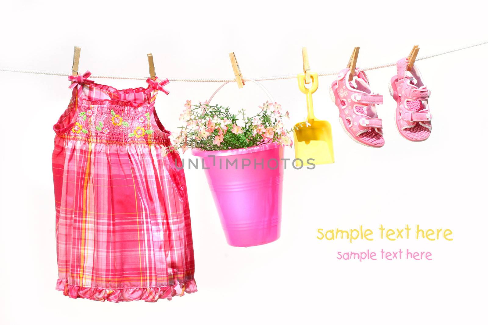 Little girl clothes and toys on a clothesline against white background