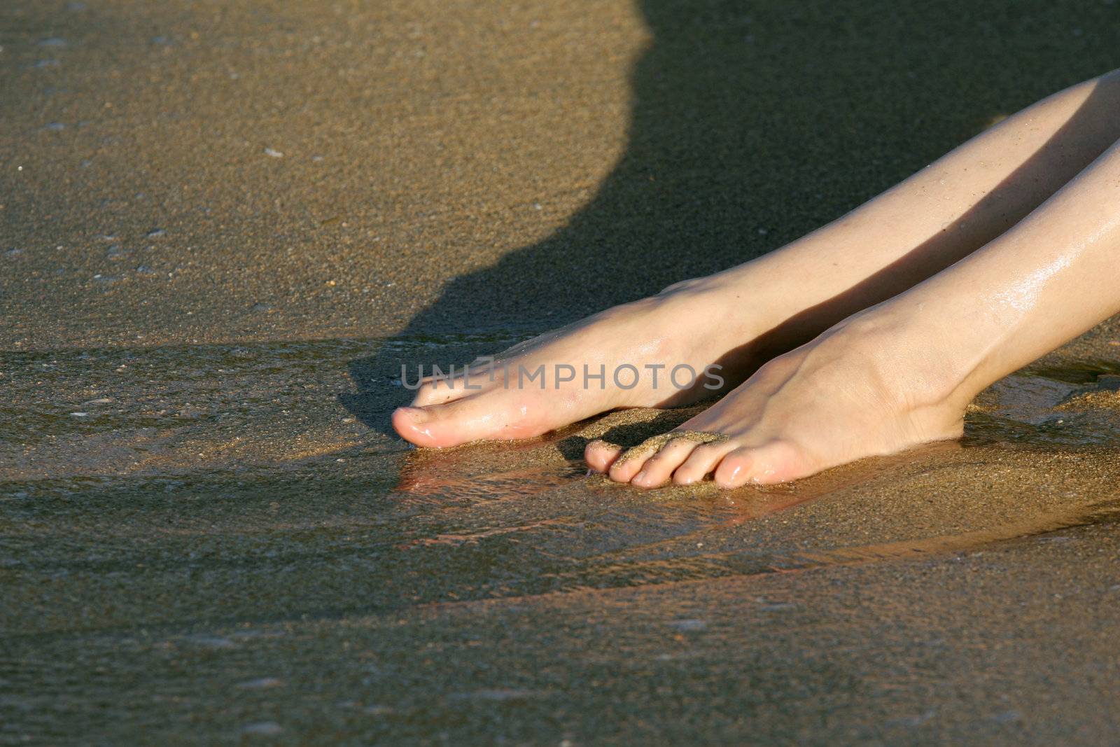 Female feet in water on the beach