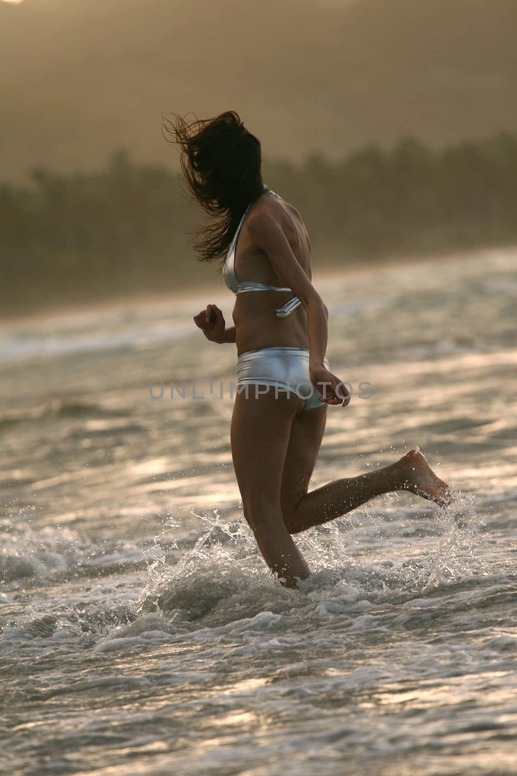 Woman in silver bikinis jogging in water