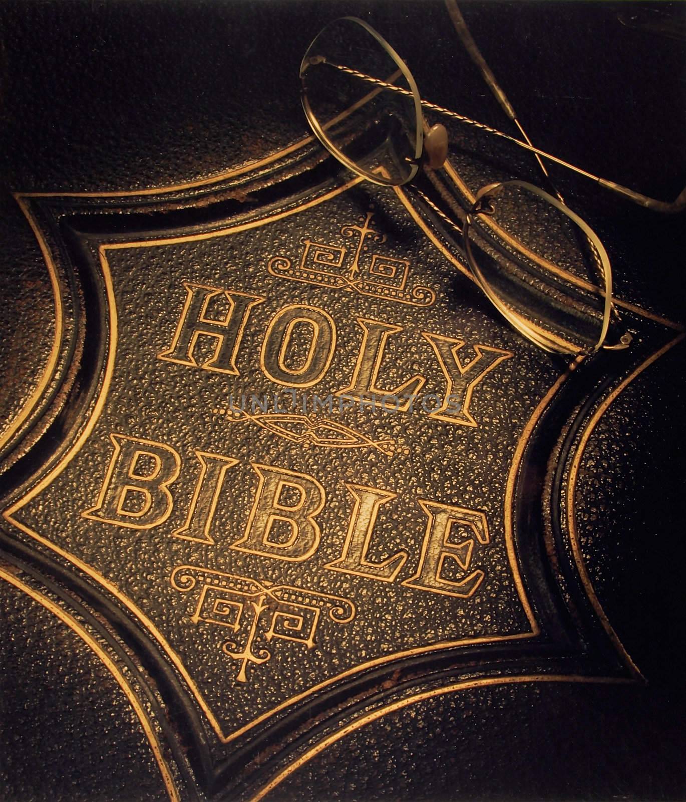 An old edition of the Holy Bible with reading glasses on it.