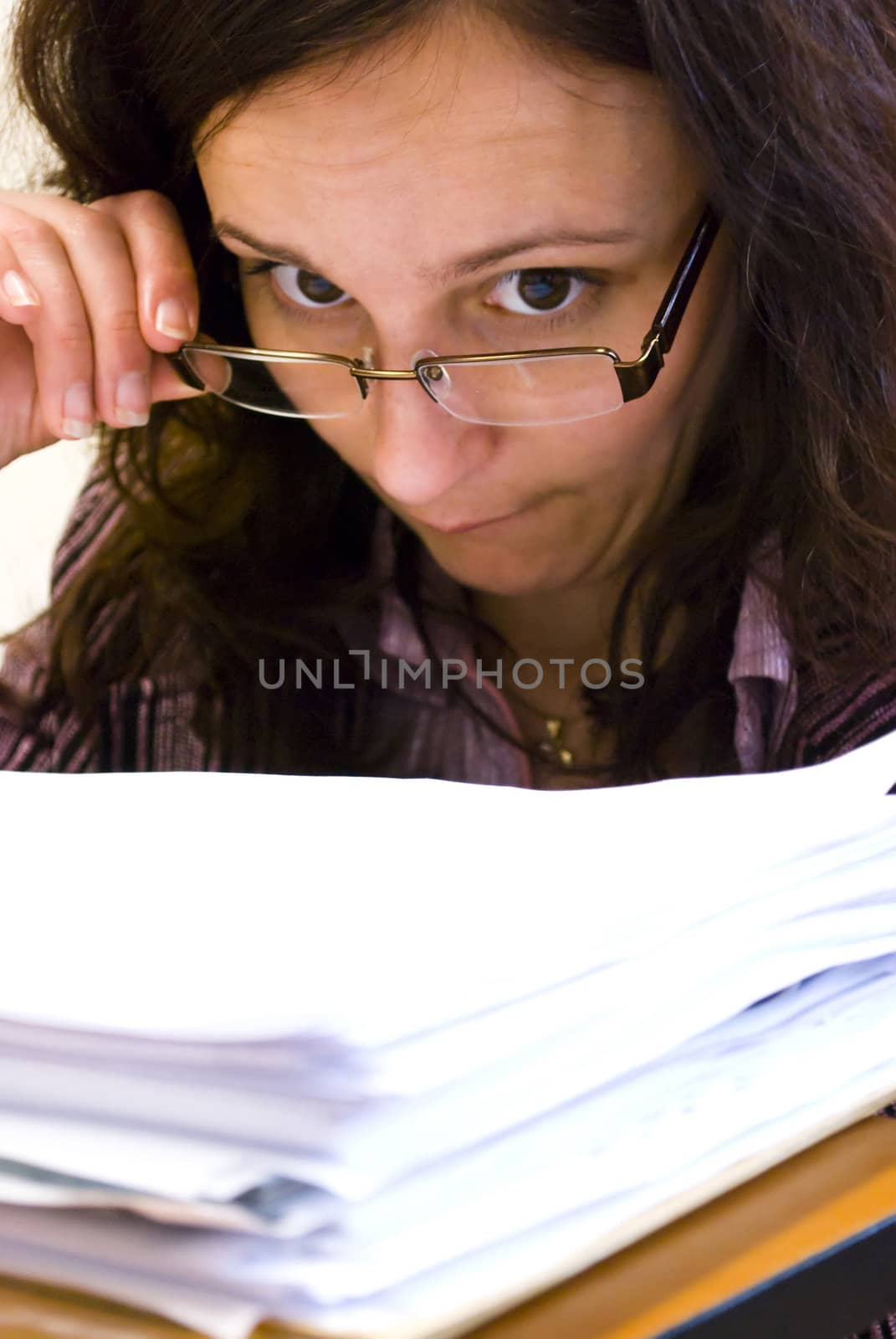 young businesswoman looking pile of documents over glasses