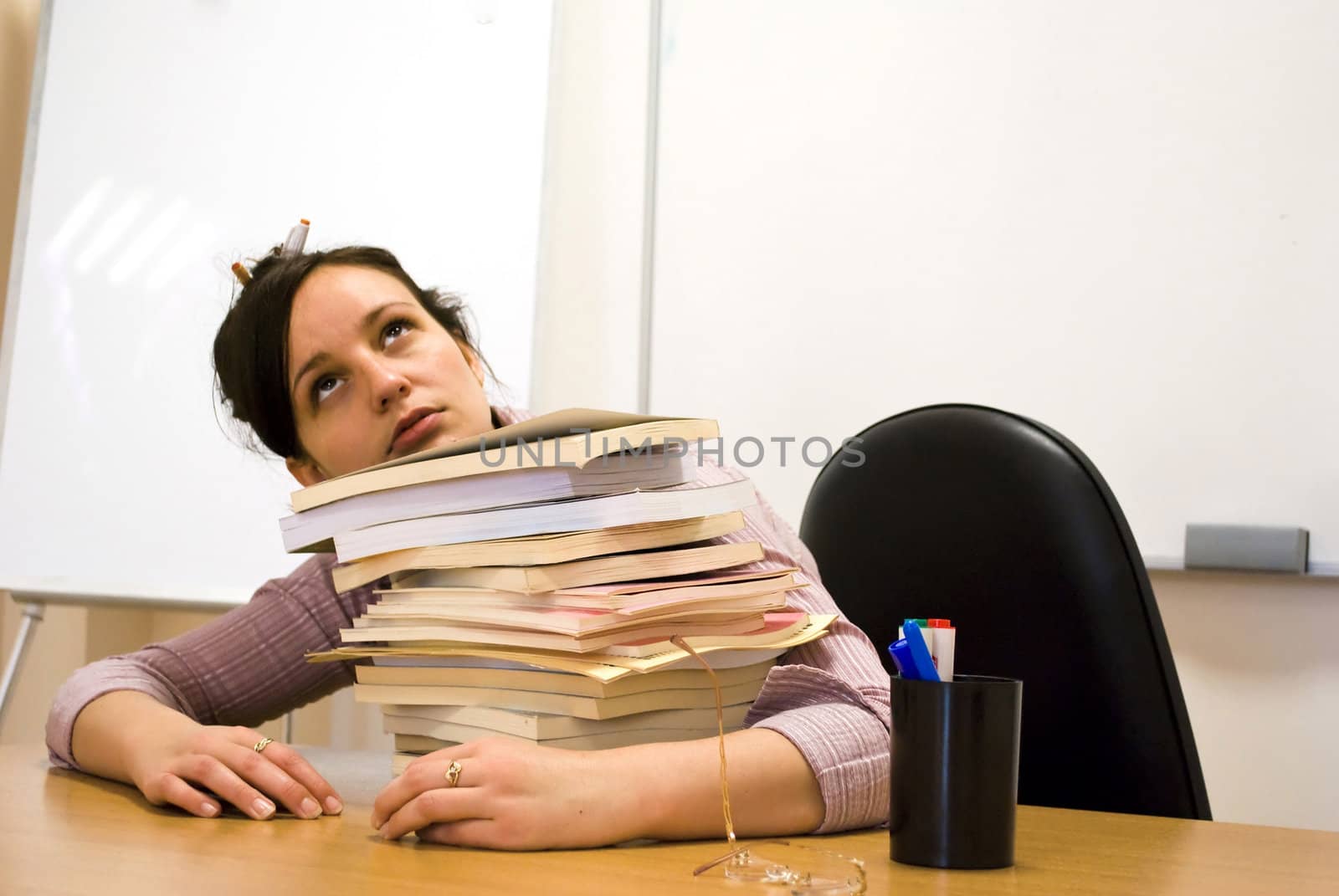 young student holding her head over books