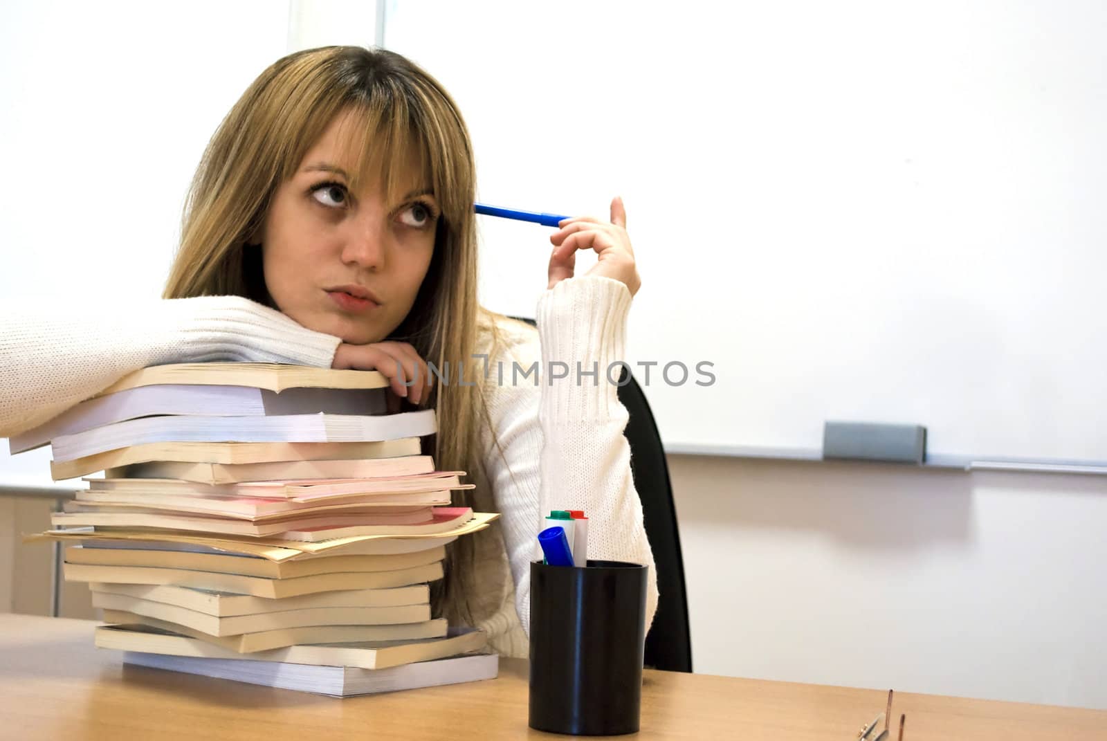 young student holding her head over books