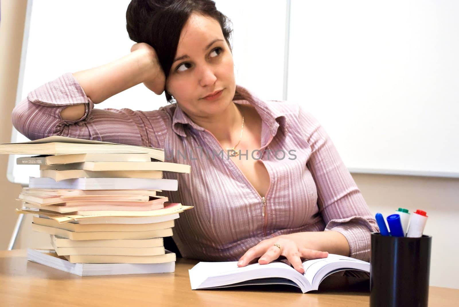 young student holding her head over books