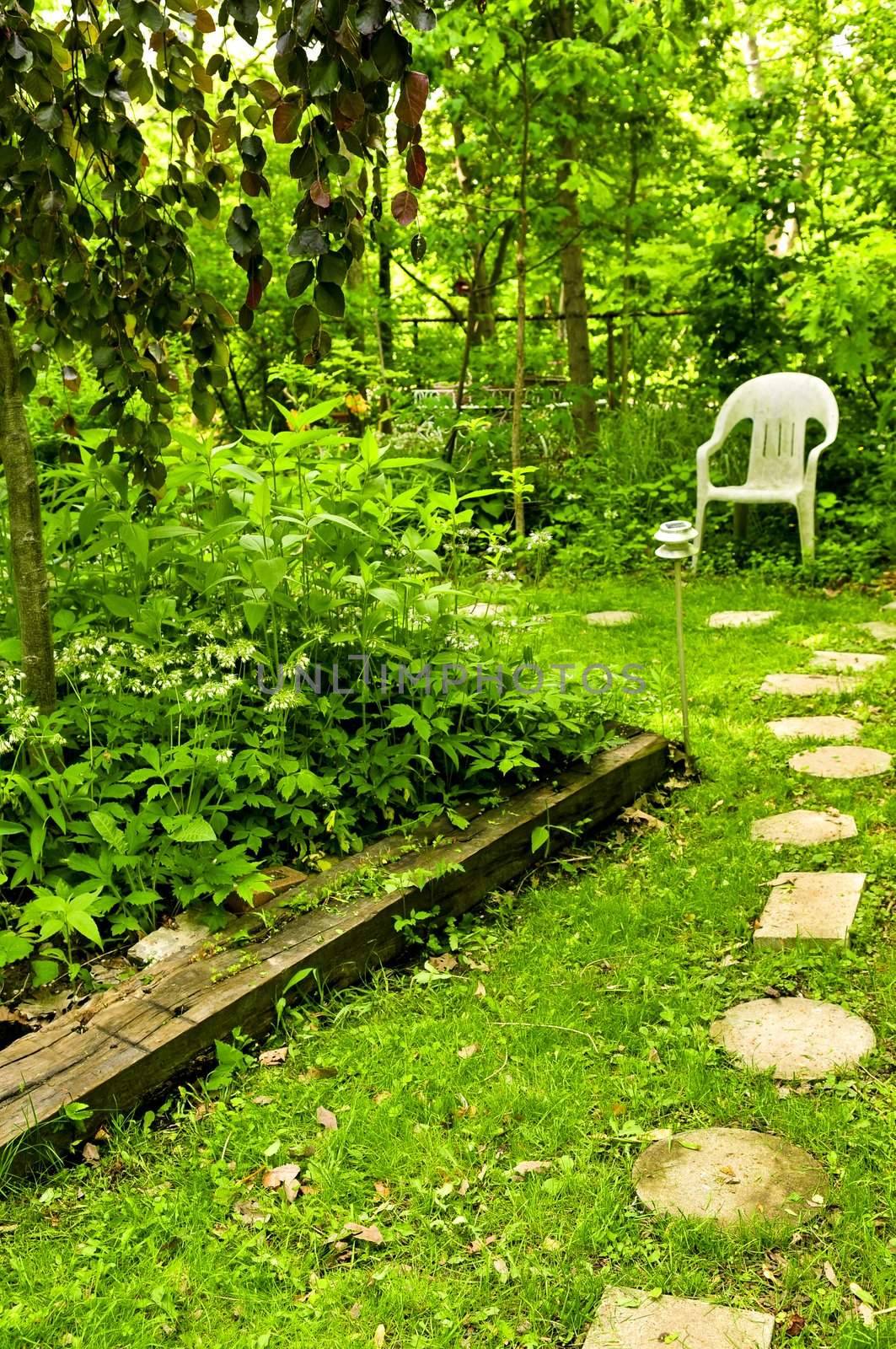 Path of stepping stones leading to secluded corner in lush green garden