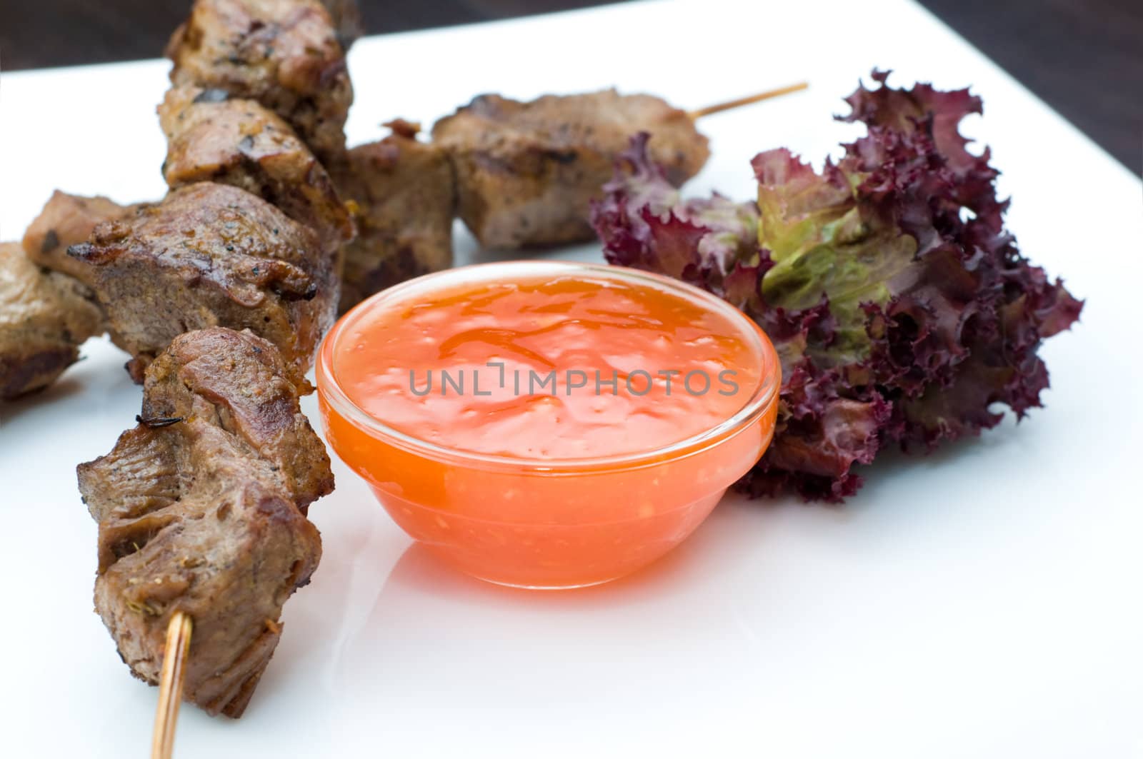 dish of fresh kebabs on sticks with hot sauce, copy space