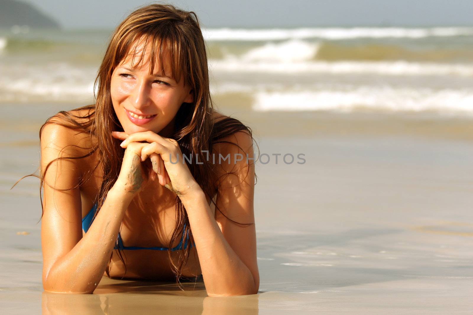 portrait of happy woman in blue bikini lying on the beach
