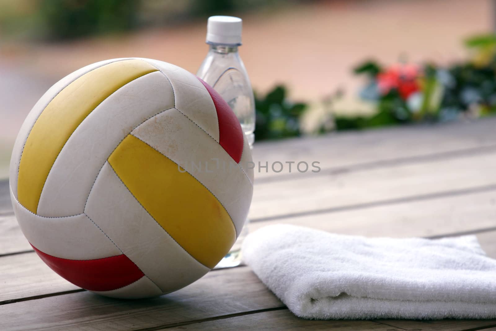 Volleyball, bottle water and towel on the wooden ground