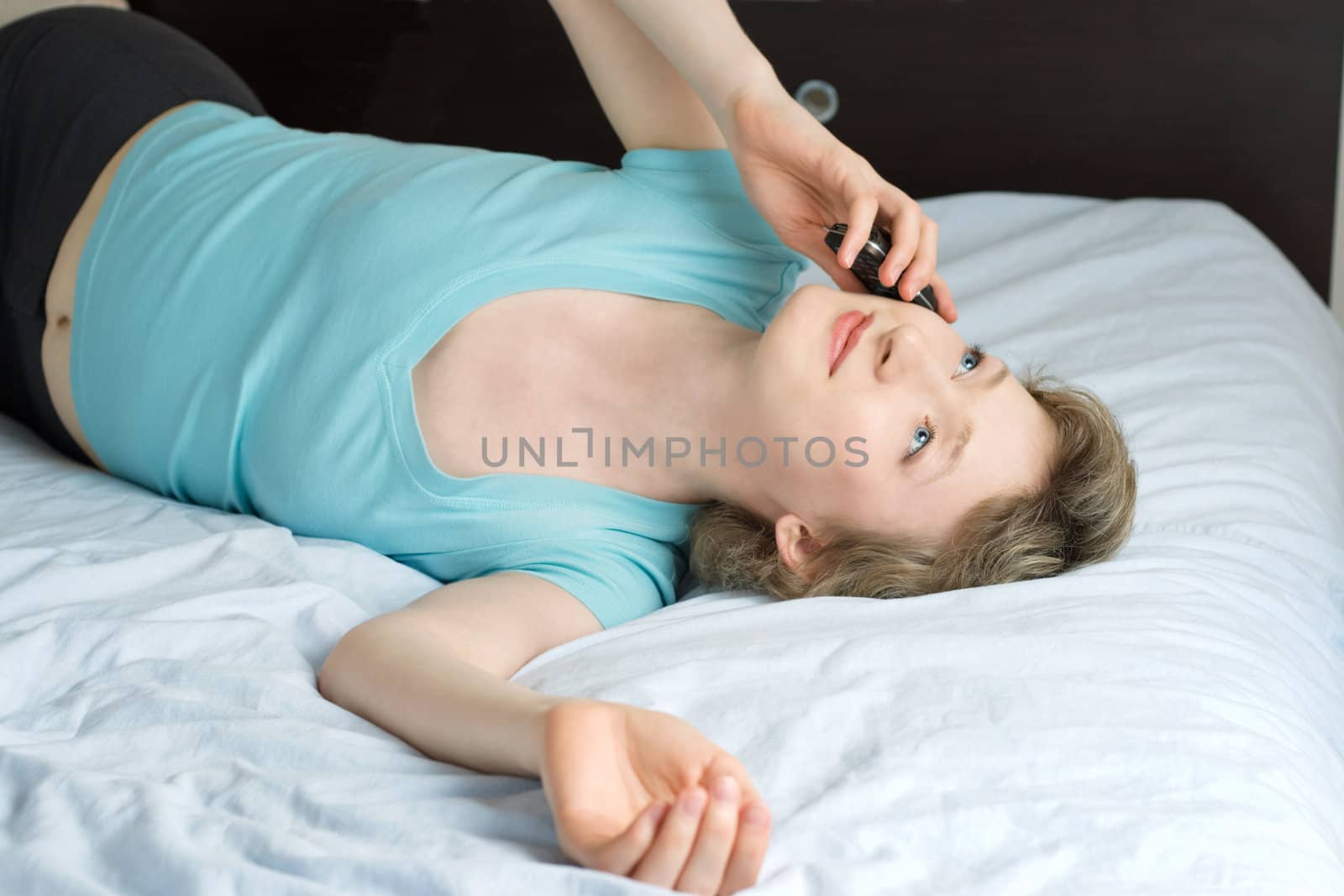 young woman with mobile phone on a bed, shallow DOF, focus on eyes