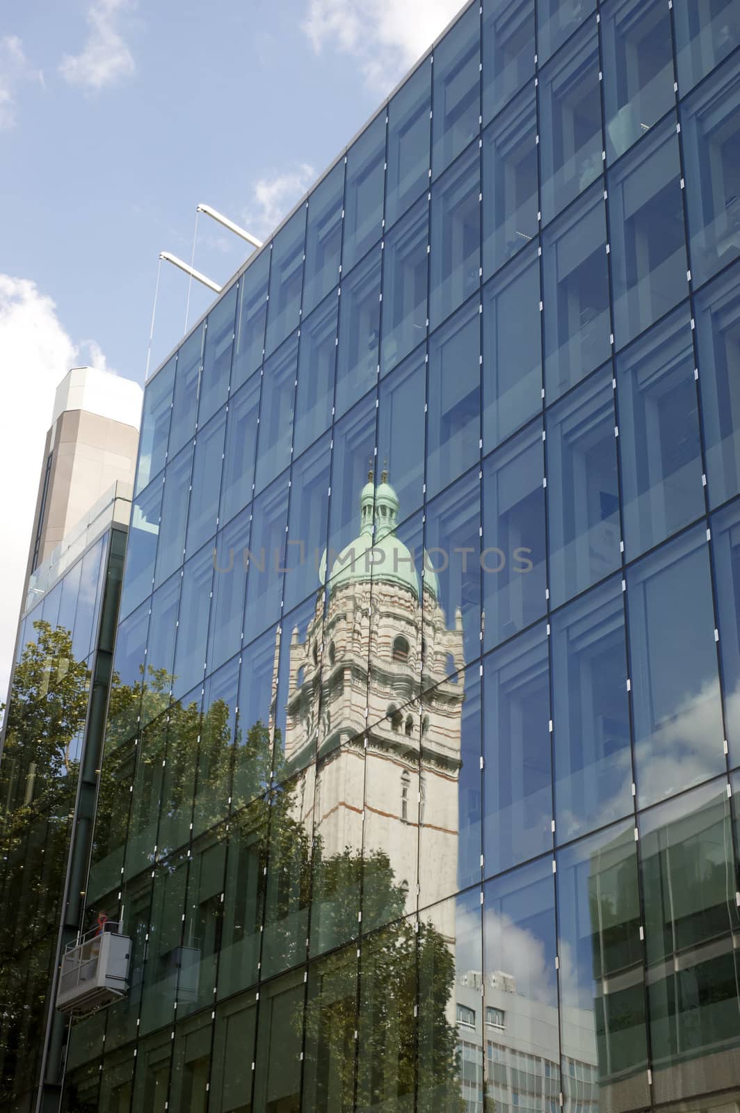 An old tower reflected in athe glass of a modern building