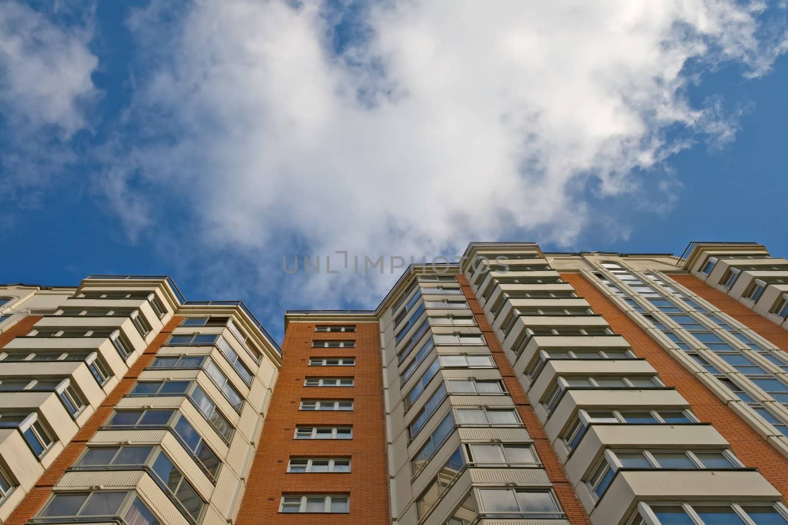 A residential multistory house and sky with clouds, view from below