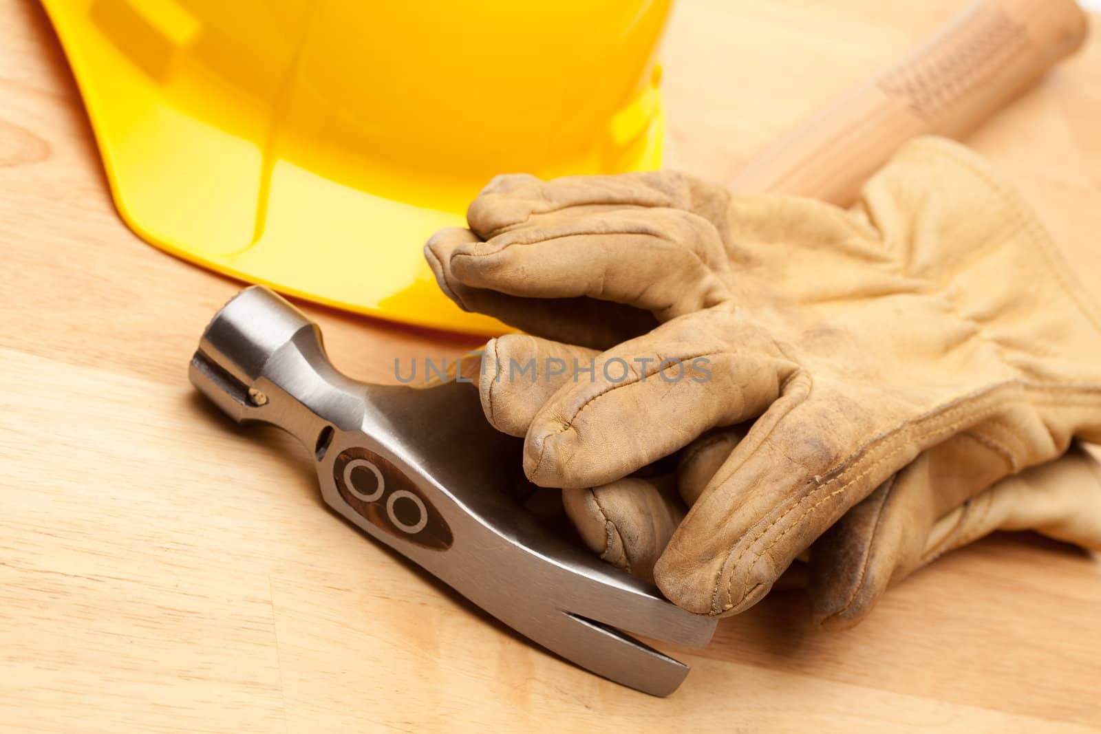 Yellow Hard Hat, Gloves and Hammer on Wood Surface.