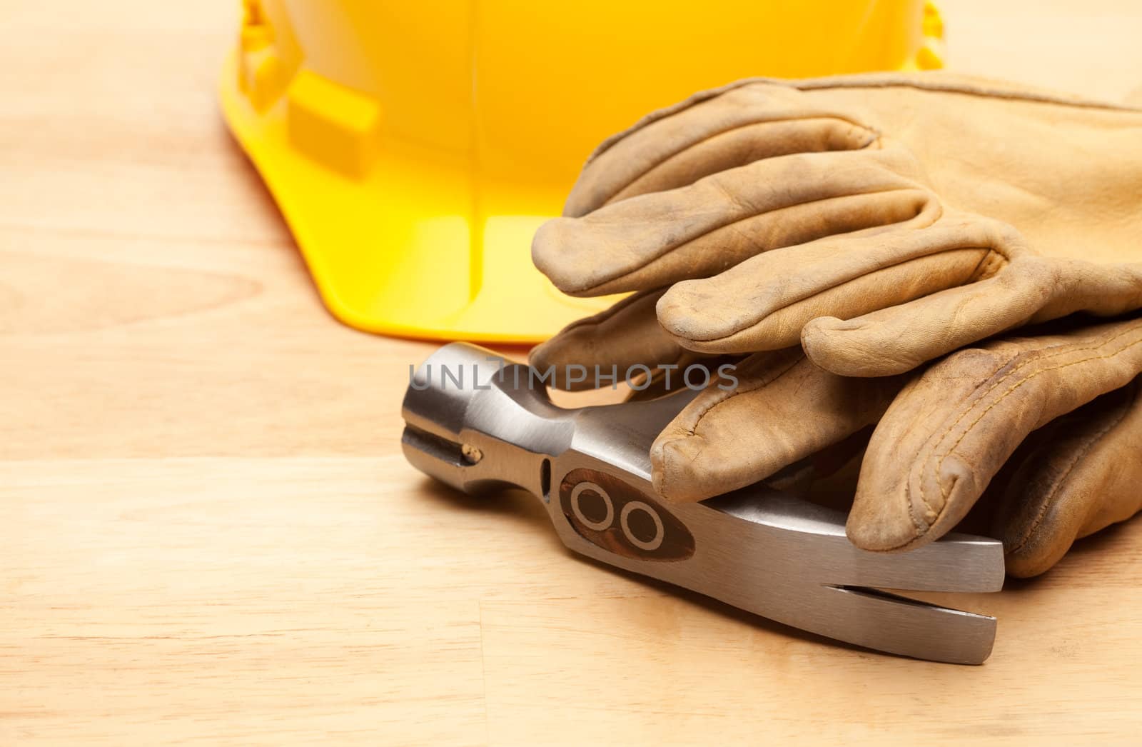 Yellow Hard Hat, Gloves and Hammer on Wood Surface.