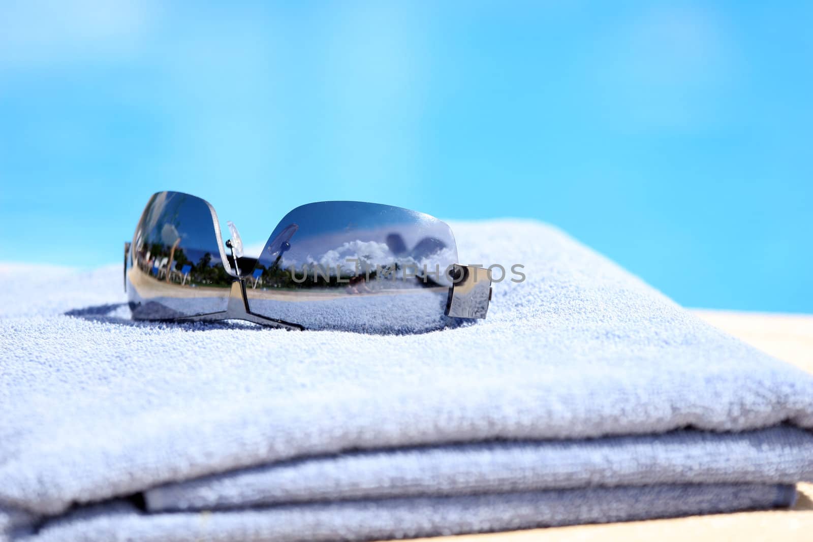 sunglasses on towel by the pool