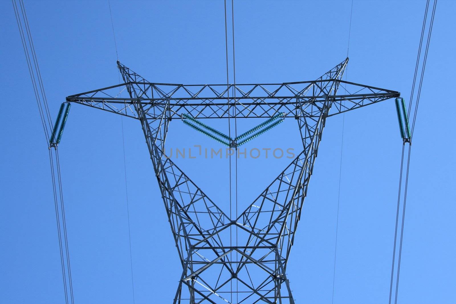 Top of the huge high voltage electricity pylon against the sky.
