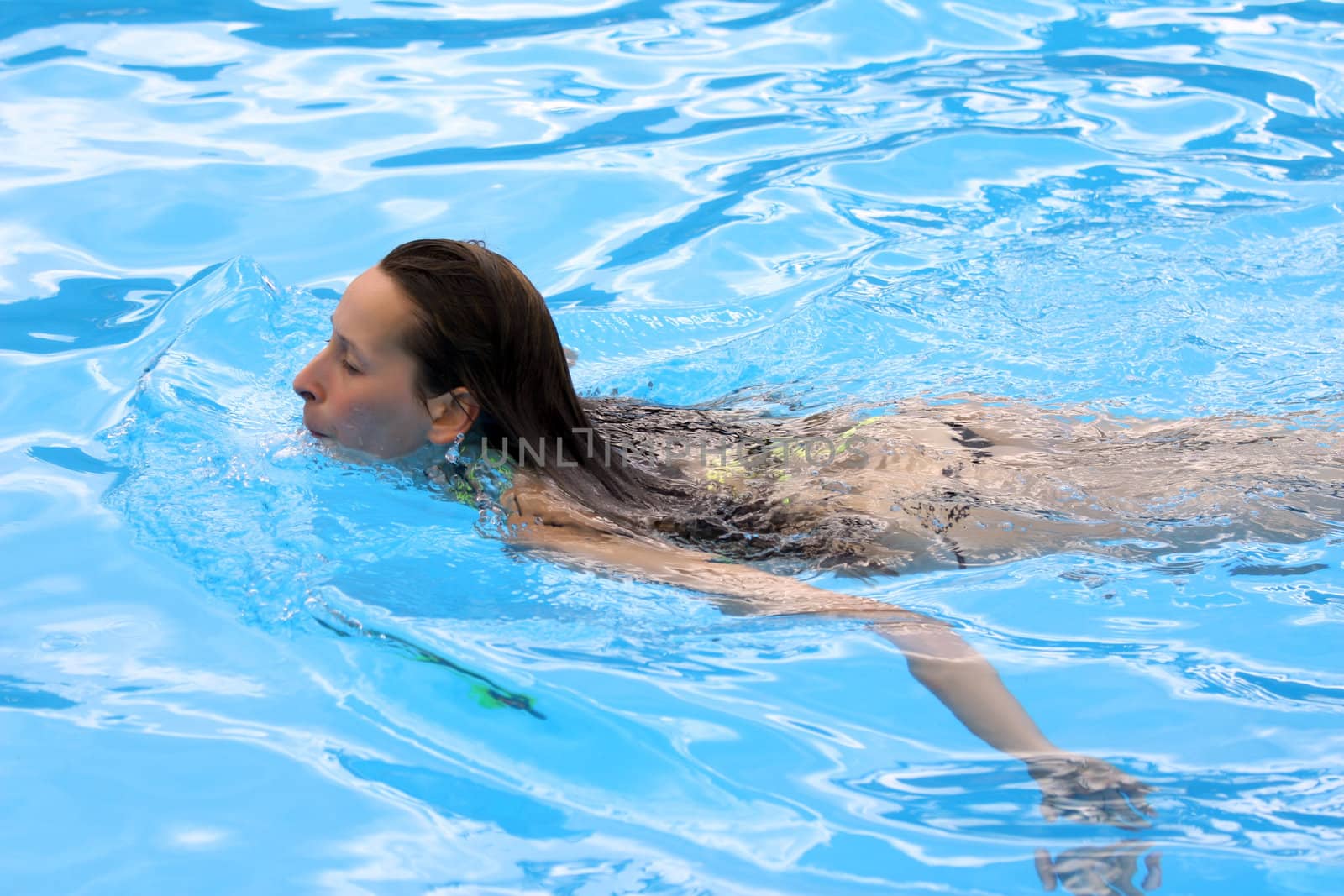 Jung woman swimming in the pool by hotel