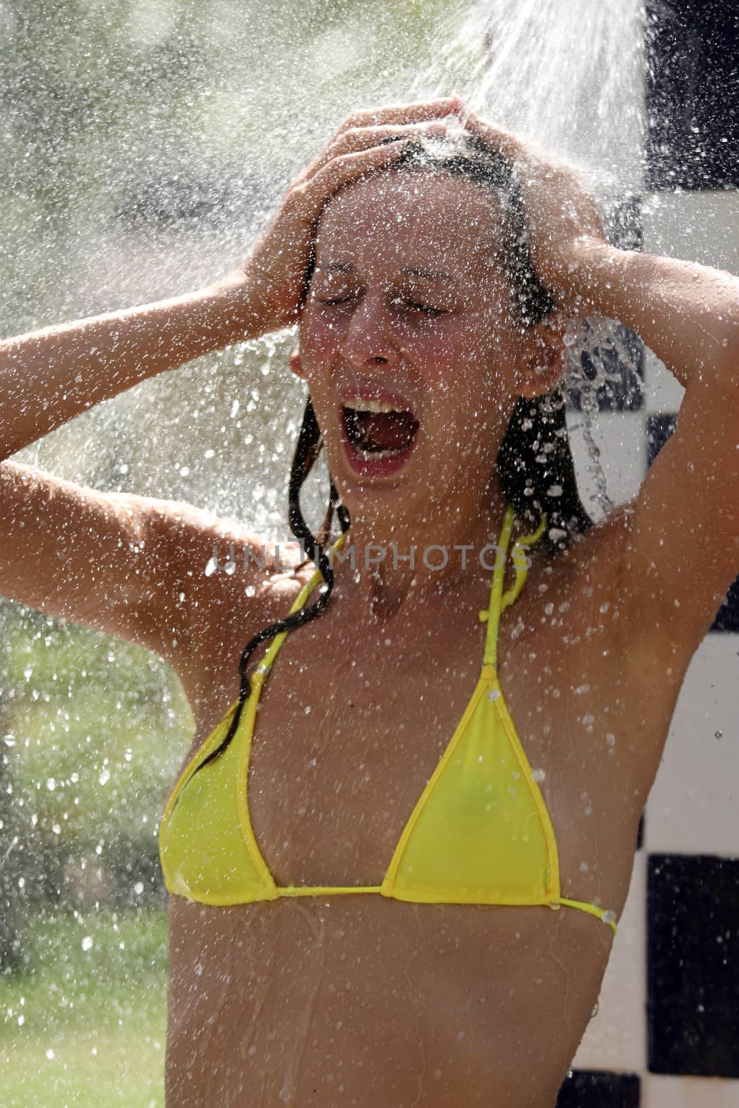 tanned woman in bikini taking shower on the beach