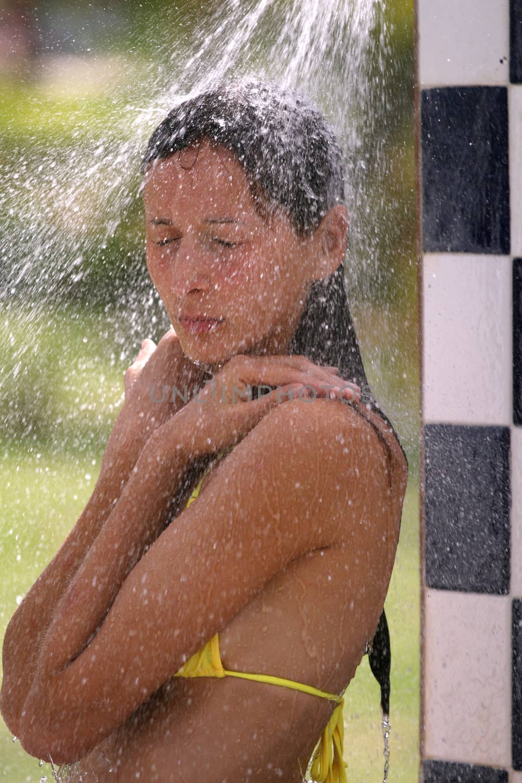 tanned woman in bikini takes shower on the beach