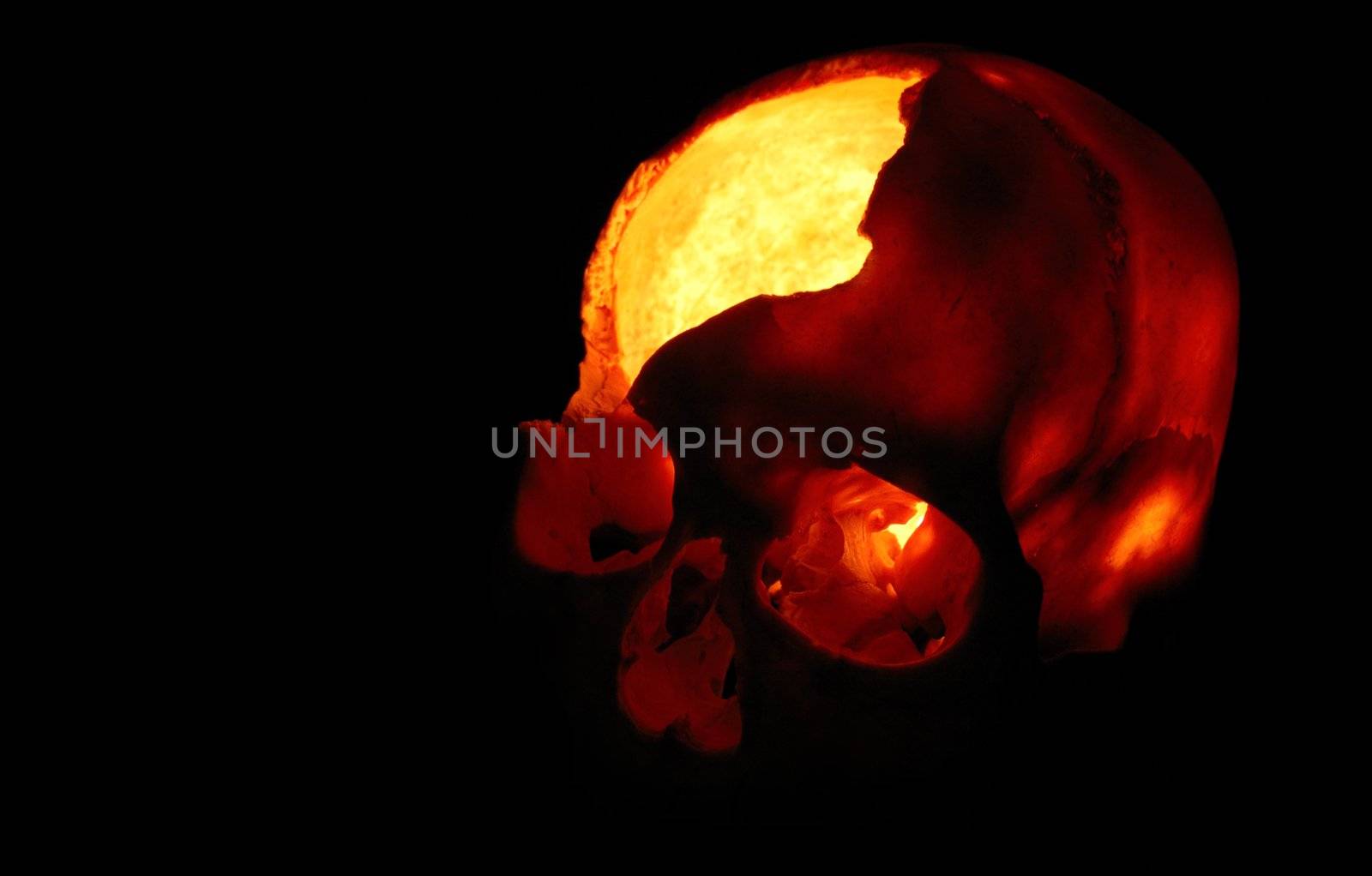 Burning skull - Old broken skull against black background with inner flame