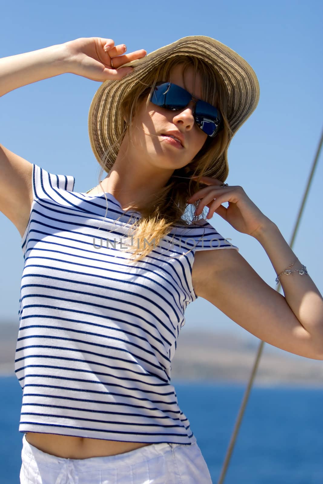 Beautiful young woman in sunglasses sailing on a boat