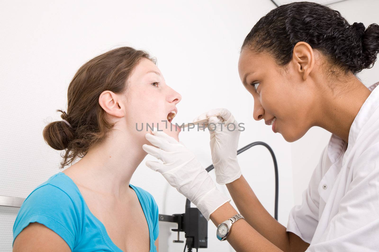 Doctor looking into the mouth of her patient with a spatula
