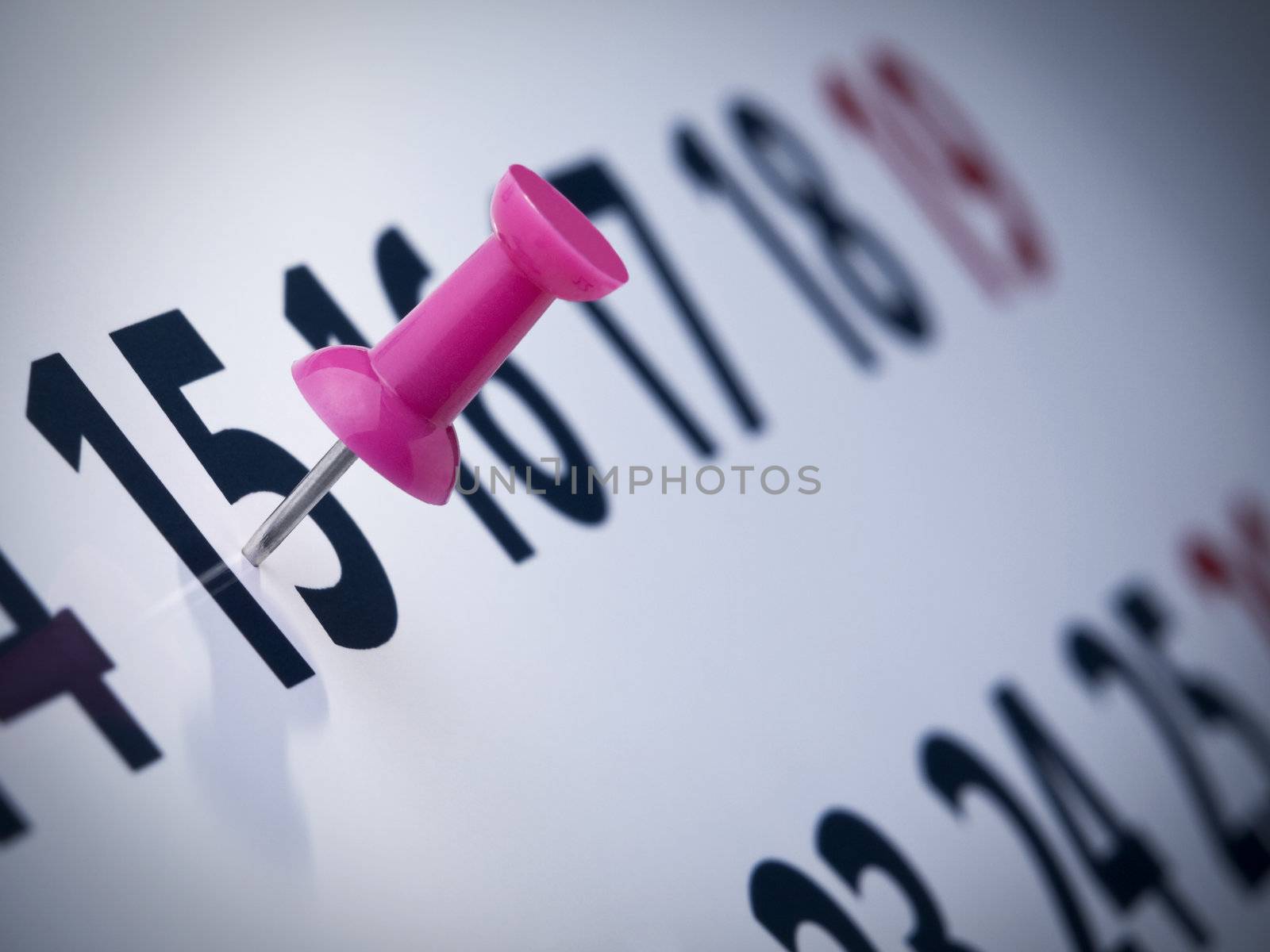 A pink push pin on the 15th day of a calendar.